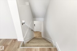 Carpeted staircase with white risers and handrails, complemented by wood-finish flooring - 