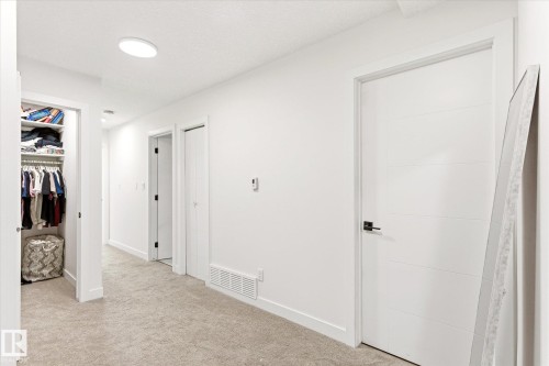 Hallway featuring light-toned carpeting and multiple white paneled doors - 108 10105 95 Street, Edmonton, AB - Indoor Photo Showing Other Room