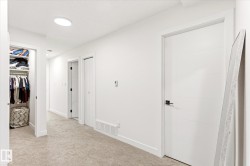 Hallway featuring light-toned carpeting and multiple white paneled doors - 
