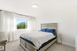 Bedroom featuring a large window, soft neutral carpet, white walls, and a contemporary ceiling light fixture - 