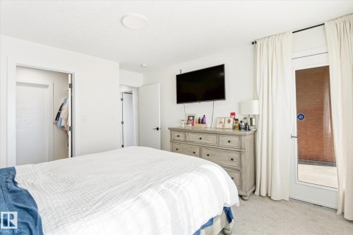 Carpeted bedroom featuring a light color palette, a ceiling light fixture, and a built-in closet with a white door - 108 10105 95 Street, Edmonton, AB - Indoor Photo Showing Bedroom