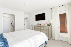 Carpeted bedroom featuring a light color palette, a ceiling light fixture, and a built-in closet with a white door - 