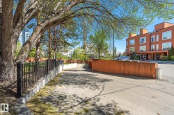 Paved driveway entrance with a black metal fence and concrete retaining walls - 