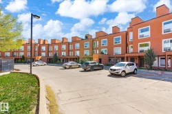 Contemporary townhome exteriors featuring multiple windows, individual entryways, and a paved parking area - 