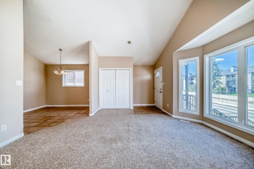 Interior living space featuring vaulted ceilings, a prominent bay window with multiple panes, and neutral-toned carpeting - 9825 156 Street, Edmonton, AB - Indoor Photo Showing Other Room