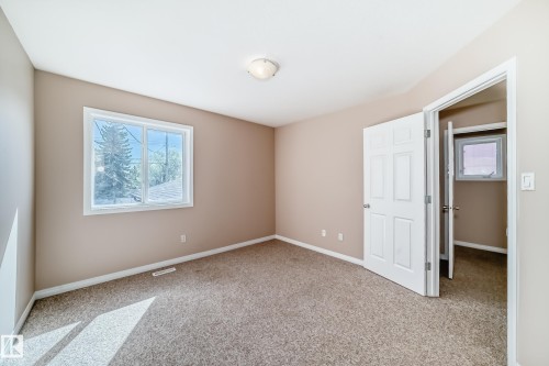 Carpeted room featuring a double-paned window, neutral wall paint, white trim, and a six-panel interior door - 9825 156 Street, Edmonton, AB - Indoor Photo Showing Other Room