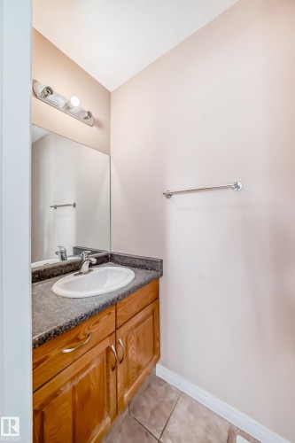 Bathroom vanity featuring a wood-finish cabinet with silver-tone hardware, a white oval sink, and a speckled countertop - 9825 156 Street, Edmonton, AB - Indoor Photo Showing Bathroom