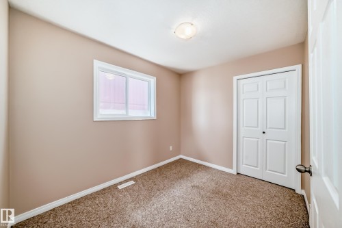 Carpeted room with a double-pane window, white trim, and a bi-fold closet door - 9825 156 Street, Edmonton, AB - Indoor Photo Showing Other Room