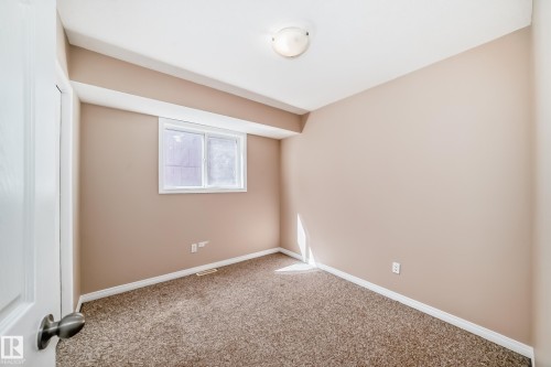 Carpeted room with a white-framed window and neutral wall tones - 9825 156 Street, Edmonton, AB - Indoor Photo Showing Other Room