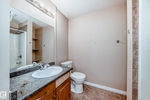Bathroom featuring a wood-finish vanity with an integrated sink and laminate countertop - 9825 156 Street, Edmonton, AB - Indoor Photo Showing Bathroom