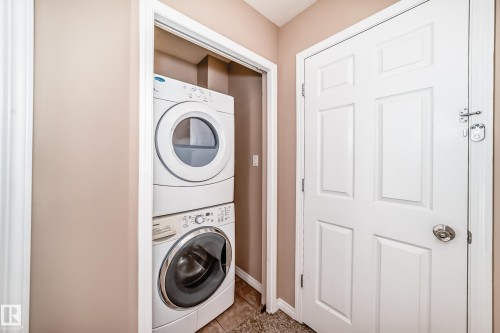 Dedicated laundry closet featuring a stacked white washer and dryer, tile flooring, and neutral wall paint - 9825 156 Street, Edmonton, AB - Indoor Photo Showing Laundry Room
