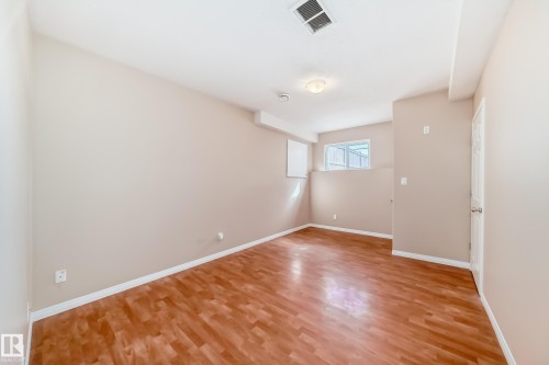 Spacious room featuring wood-finish flooring, light neutral wall paint, and white baseboards - 9825 156 Street, Edmonton, AB - Indoor Photo Showing Other Room