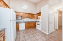Kitchen featuring wood cabinetry, white appliances, tile flooring, and a vaulted ceiling with a chandelier - 9825 156 Street, Edmonton, AB  - Indoor Photo Showing Kitchen 