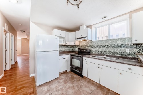 Kitchen featuring white cabinetry, dark countertops, a mosaic tile backsplash, and a double basin sink - 9825 156 Street, Edmonton, AB - Indoor Photo Showing Kitchen With Double Sink