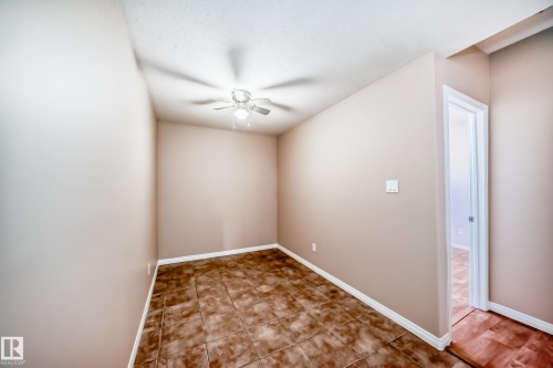 Compact room featuring neutral painted walls, brown-toned tile flooring, and a ceiling fan with integrated lighting - 9825 156 Street, Edmonton, AB - Indoor Photo Showing Other Room