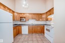 Kitchen featuring extensive wood cabinetry, tile flooring, and white appliances - 9825 156 Street, Edmonton, AB  - Indoor Photo Showing Kitchen With Double Sink 