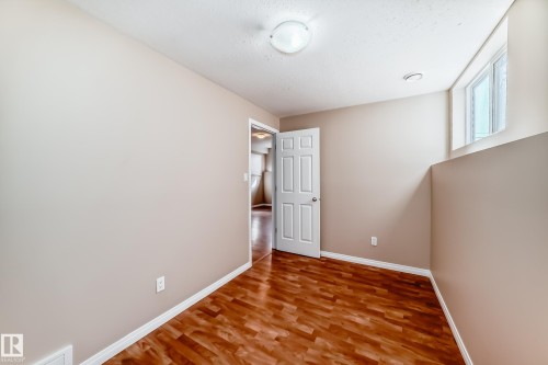 Room featuring wood-finish flooring, neutral wall paint, and a white four-panel door - 9825 156 Street, Edmonton, AB - Indoor Photo Showing Other Room