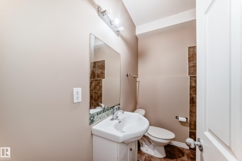 Bathroom featuring a white vanity with integrated sink, chrome faucet, wall-mounted mirror, and decorative tile accents - 9825 156 Street, Edmonton, AB - Indoor Photo Showing Bathroom