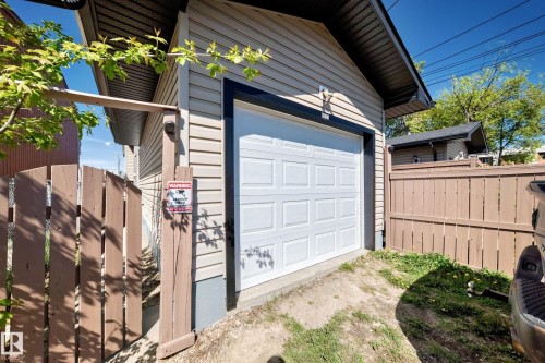 Detached garage with a white panel door, light-colored siding, and dark trim - 9825 156 Street, Edmonton, AB - Outdoor With Exterior