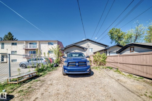 Gravel driveway with a wood fence and a detached garage featuring siding exterior - 9825 156 Street, Edmonton, AB - Outdoor