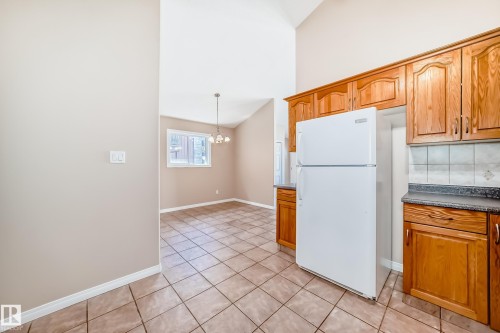 Kitchen featuring wood-finish cabinetry, tile flooring, and a white refrigerator - 9825 156 Street, Edmonton, AB - Indoor Photo Showing Kitchen