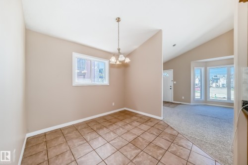 Tiled flooring with a white trim baseboard, illuminated by a multi-bulb chandelier - 9825 156 Street, Edmonton, AB - Indoor Photo Showing Other Room