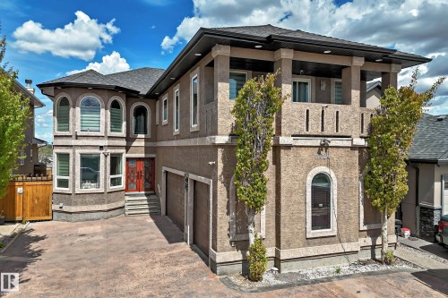 Stucco exterior with an upper-level balcony, arched and rectangular windows, and a stamped concrete driveway - 11024 179 Avenue, Edmonton, AB - Outdoor With Facade