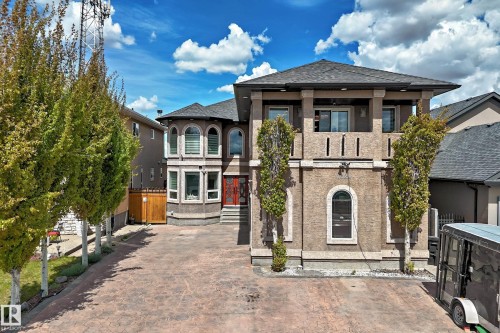Stucco exterior featuring a double door entry way, stamped concrete driveway, and mature landscaping - 11024 179 Avenue, Edmonton, AB - Outdoor