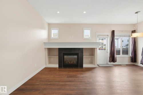 Living space featuring a built-in fireplace with black surround, integrated shelving, and a substantial mantel - 2917 16A Avenue, Edmonton, AB - Indoor Photo Showing Living Room With Fireplace