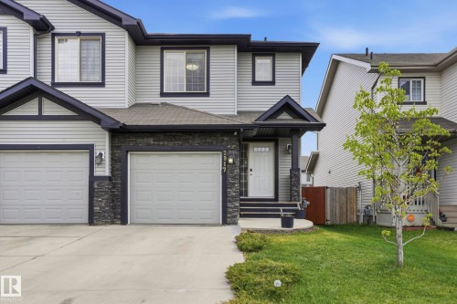 Contemporary exterior featuring light-colored siding with dark trim, a stone accent facade, and a covered front entry - 2917 16A Avenue, Edmonton, AB - Outdoor