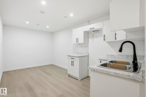Kitchenette featuring white cabinetry with matte black hardware, dual stainless steel sink, black gooseneck faucet, and light-toned countertops - 2917 16A Avenue, Edmonton, AB - Indoor Photo Showing Kitchen With Double Sink
