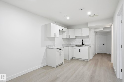 Compact kitchen area featuring white cabinetry, light-toned countertops, a matte black faucet, and wood-finish flooring - 2917 16A Avenue, Edmonton, AB - Indoor Photo Showing Kitchen