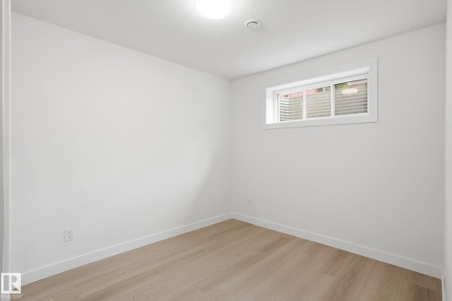 Crisp white walls frame this versatile room, featuring light wood-finish flooring, a white window with horizontal blinds, and a flush-mount ceiling light fixture - 2917 16A Avenue, Edmonton, AB - Indoor Photo Showing Other Room