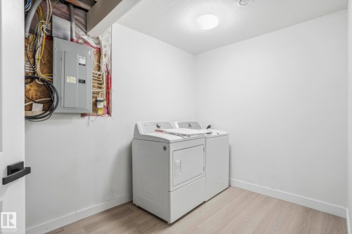 Dedicated utility space featuring light wood-finish flooring, white painted walls, and a contemporary flush-mount ceiling light fixture - 2917 16A Avenue, Edmonton, AB - Indoor Photo Showing Laundry Room