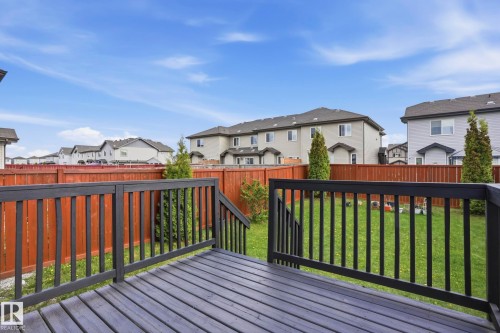 Spacious backyard featuring a dark-stained wood deck with black railings, a full-height wood fence, and a manicured lawn - 2917 16A Avenue, Edmonton, AB - Outdoor With Deck Patio Veranda With Exterior