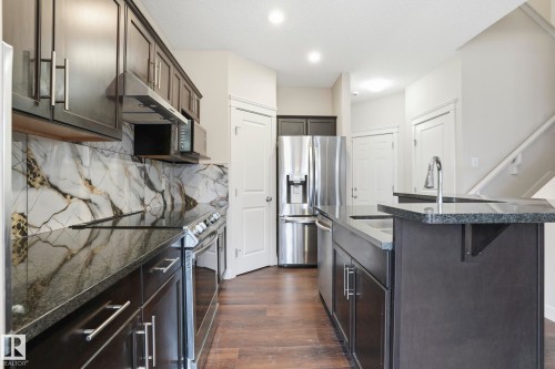 Kitchen featuring dark cabinetry, stainless steel appliances, and a contrasting marble-patterned backsplash - 2917 16A Avenue, Edmonton, AB - Indoor Photo Showing Kitchen With Stainless Steel Kitchen With Upgraded Kitchen