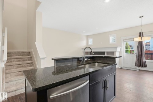 Kitchen island with dark granite countertops, double basin sink, and integrated stainless steel dishwasher - 2917 16A Avenue, Edmonton, AB - Indoor Photo Showing Kitchen With Double Sink