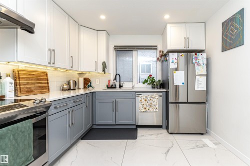 Contemporary kitchen featuring two-tone cabinetry, stainless steel appliances, white quartz countertops, and a subway tile backsplash - 17716 84 Ave, Edmonton, AB - Indoor Photo Showing Kitchen With Upgraded Kitchen