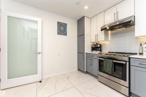 Kitchen featuring a stainless steel range with overhead hood, light grey and white cabinetry, white countertops, and a subway tile backsplash - 17716 84 Ave, Edmonton, AB - Indoor Photo Showing Kitchen With Upgraded Kitchen