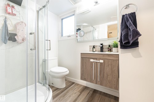 Bathroom featuring a glass-enclosed shower, a wood-finish vanity with a white countertop, and a rectangular mirror - 17716 84 Ave, Edmonton, AB - Indoor Photo Showing Bathroom