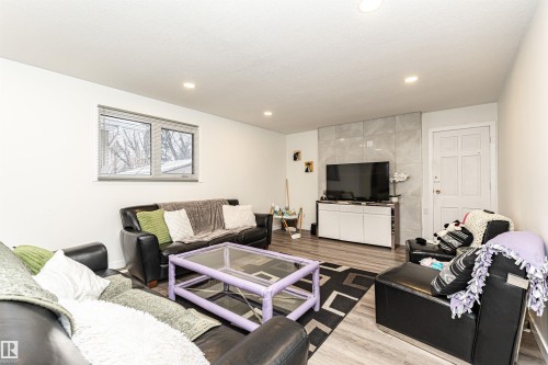 Recessed lighting illuminates this living area featuring wood-finish flooring and a window with blinds - 17716 84 Ave, Edmonton, AB - Indoor Photo Showing Living Room