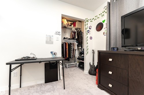 Carpeted room with a built-in closet featuring wire shelving and hanging rods - 17716 84 Ave, Edmonton, AB - Indoor