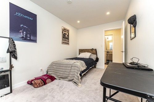 Bright room with light gray carpet, recessed lighting, and a white door leading to a bathroom with a vanity and mirror - 17716 84 Ave, Edmonton, AB - Indoor Photo Showing Bedroom