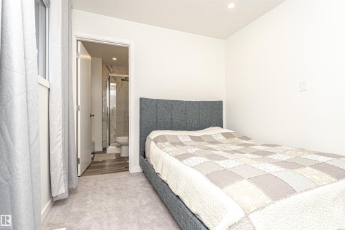 Carpeted sleeping area with white walls and a window featuring light-colored curtains - 17716 84 Ave, Edmonton, AB - Indoor Photo Showing Bedroom