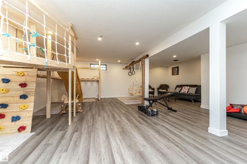 Lower level featuring wood-finish flooring, recessed lighting, and a built-in play structure with a climbing wall and slide - 17716 84 Ave, Edmonton, AB - Indoor Photo Showing Gym Room