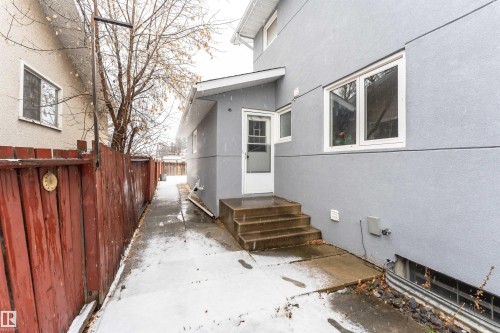 Gray stucco exterior with white-framed windows, a white entry door, and concrete steps - 17716 84 Ave, Edmonton, AB - Outdoor With Exterior