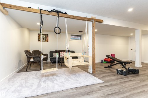 Versatile finished basement featuring wood-finish flooring, recessed lighting, and a structural wood beam accent - 17716 84 Ave, Edmonton, AB - Indoor Photo Showing Gym Room