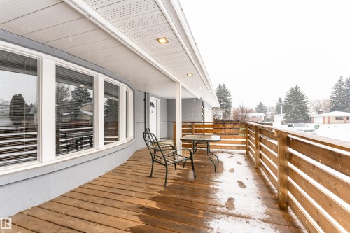 Front porch featuring a wood-finish deck, horizontal slat railing, and recessed ceiling lighting - 17716 84 Ave, Edmonton, AB - Outdoor With Deck Patio Veranda