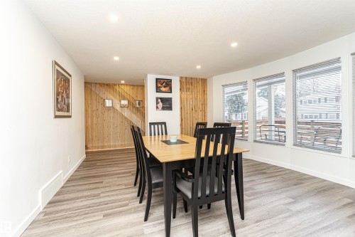 Dining area featuring light wood-finish flooring, recessed ceiling lighting, and a slatted wood accent wall - 17716 84 Ave, Edmonton, AB - Indoor Photo Showing Dining Room