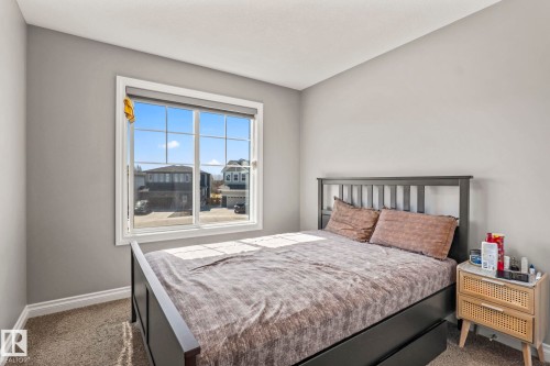 Room featuring a large window with white trim, light gray walls, and textured carpeting - 5142 23A Avenue, Edmonton, AB - Indoor Photo Showing Bedroom
